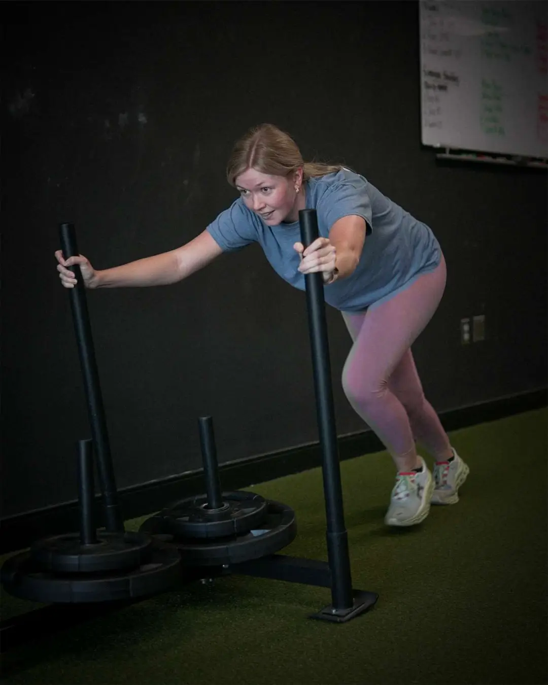 Total body cardio training - woman performing high-intensity sled workout for maximum calorie burn at Galaxy Fit Lab Naples